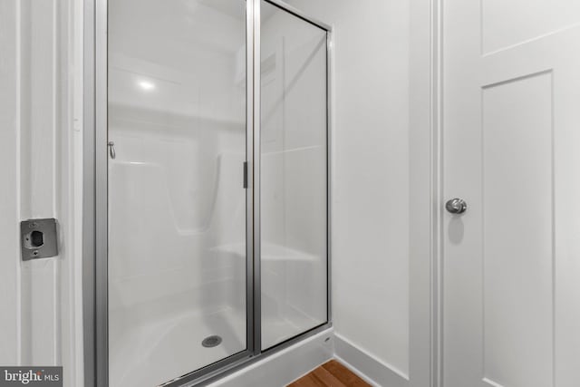 bathroom featuring wood-type flooring and a shower with shower door