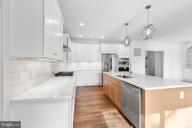 kitchen featuring white cabinets, a center island with sink, sink, light stone countertops, and stainless steel appliances