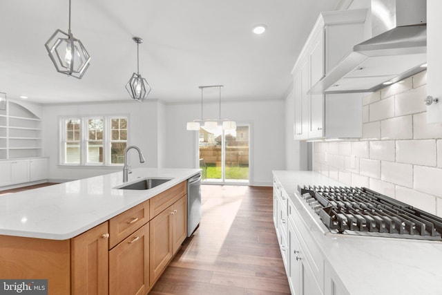 kitchen with wall chimney exhaust hood, stainless steel appliances, sink, white cabinetry, and plenty of natural light