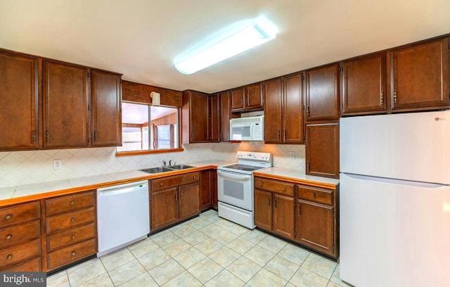 kitchen featuring white appliances, tile counters, and sink