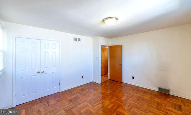 unfurnished bedroom featuring dark parquet flooring and a closet