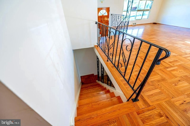 stairway featuring parquet flooring