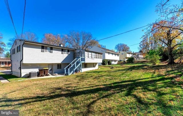 back of property featuring a sunroom, cooling unit, and a lawn