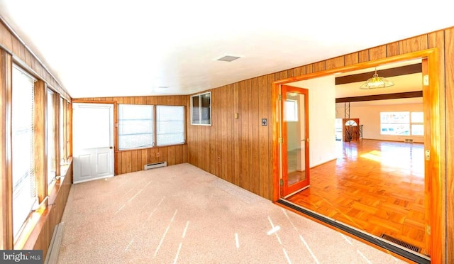 unfurnished room with a baseboard radiator and wood walls