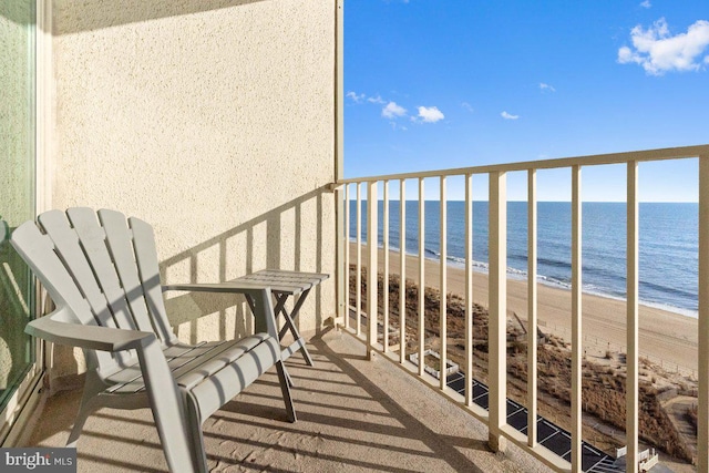 balcony with a water view and a view of the beach