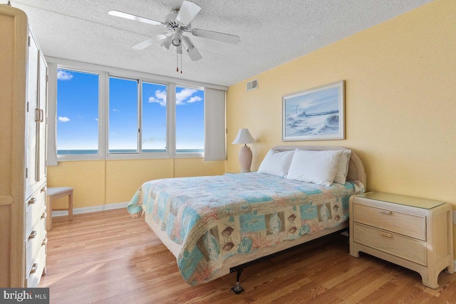 bedroom featuring ceiling fan, a textured ceiling, and light hardwood / wood-style flooring