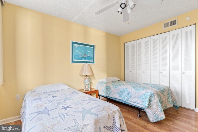 bedroom featuring hardwood / wood-style floors, a textured ceiling, a closet, and ceiling fan