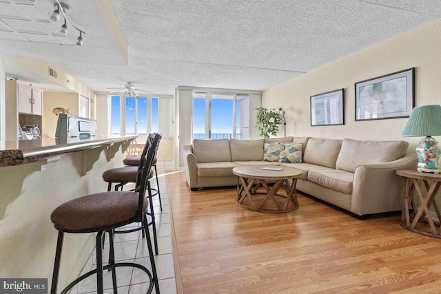 living room featuring a textured ceiling, light hardwood / wood-style flooring, and ceiling fan