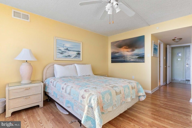 bedroom featuring ceiling fan, light hardwood / wood-style floors, and a textured ceiling