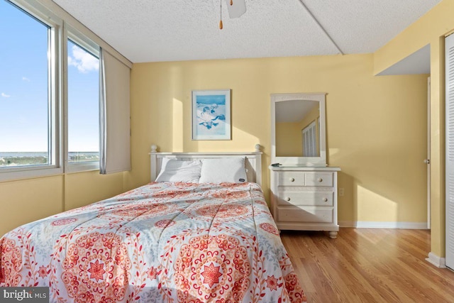 bedroom with multiple windows, ceiling fan, a textured ceiling, and hardwood / wood-style flooring