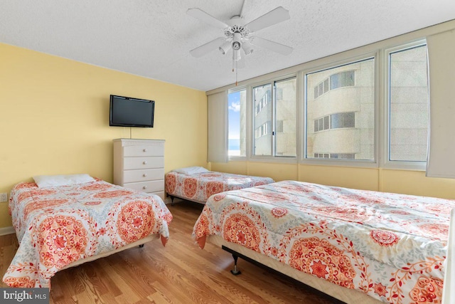 bedroom featuring ceiling fan, hardwood / wood-style floors, and a textured ceiling