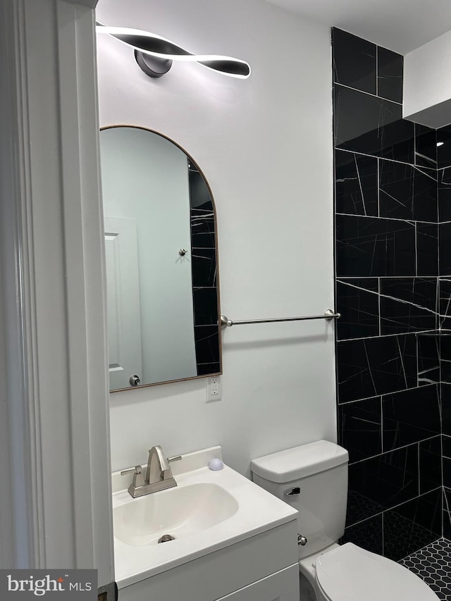 bathroom featuring tiled shower, vanity, and toilet