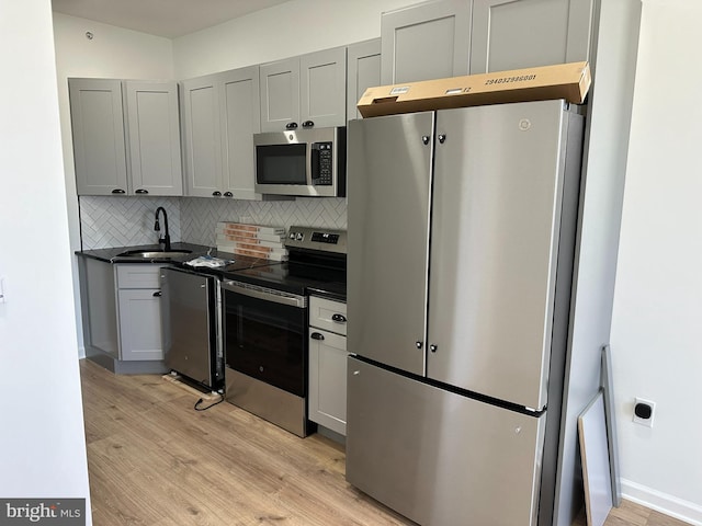 kitchen with decorative backsplash, stainless steel appliances, sink, light hardwood / wood-style flooring, and gray cabinets