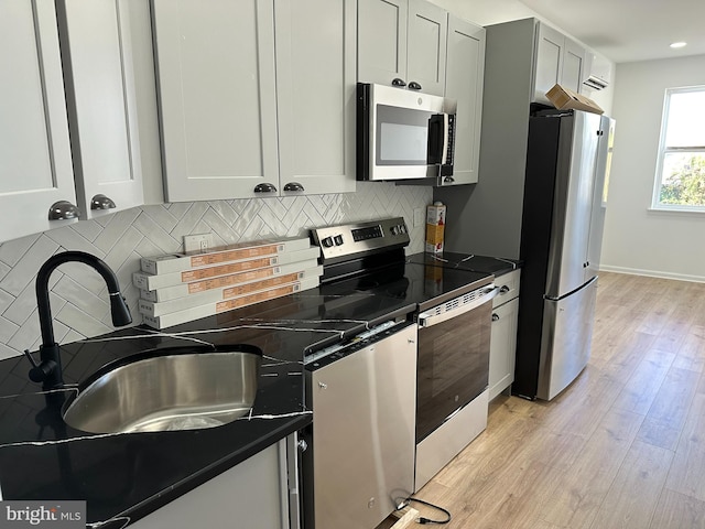 kitchen with tasteful backsplash, dark stone countertops, light hardwood / wood-style flooring, and stainless steel appliances