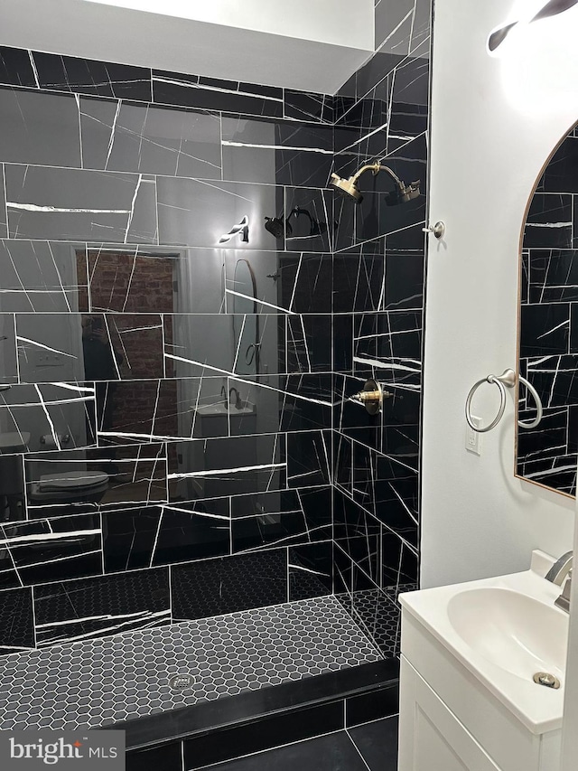 bathroom featuring a tile shower, tile patterned flooring, and vanity