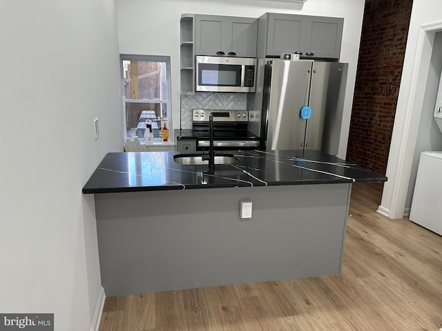 2215 N 10th St, Philadelphia, PA 19133 - kitchen with stainless steel appliances, light wood-style flooring, dark countertops, and decorative backsplash