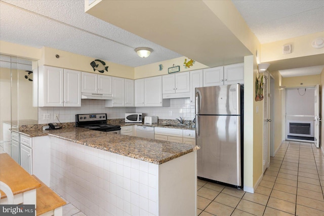 kitchen featuring white cabinetry, kitchen peninsula, appliances with stainless steel finishes, and dark stone counters