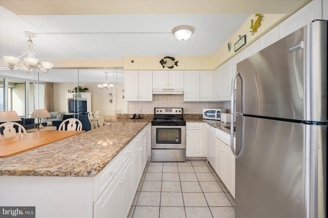 kitchen with white cabinets, appliances with stainless steel finishes, tasteful backsplash, a notable chandelier, and kitchen peninsula