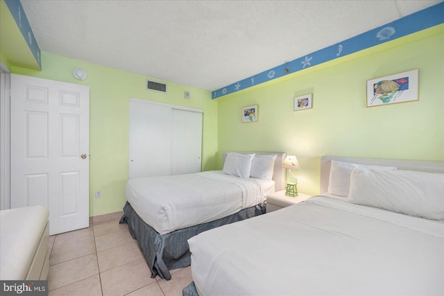 bedroom with a closet, light tile patterned floors, and a textured ceiling