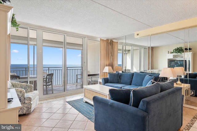 living room with light tile patterned flooring, a water view, and a textured ceiling