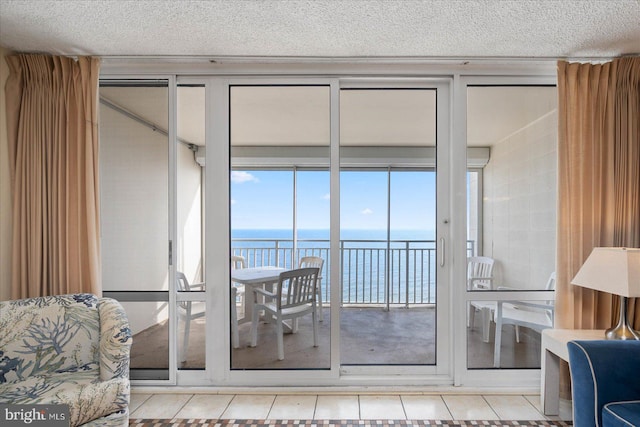 doorway to outside with light tile patterned flooring, a water view, and a textured ceiling