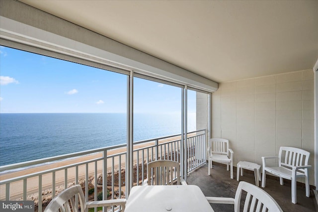 sunroom featuring a water view and a beach view