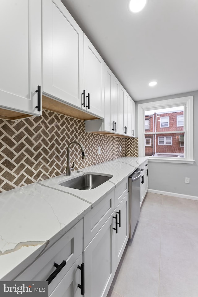 kitchen with dishwasher, sink, decorative backsplash, light stone countertops, and white cabinetry