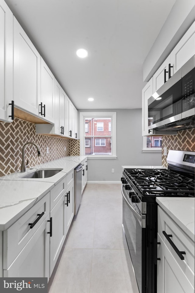 kitchen with sink, decorative backsplash, light stone countertops, white cabinetry, and stainless steel appliances