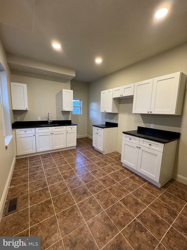 kitchen featuring white cabinets, sink, and dark tile patterned flooring