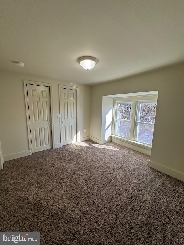 unfurnished bedroom with carpet flooring and multiple closets