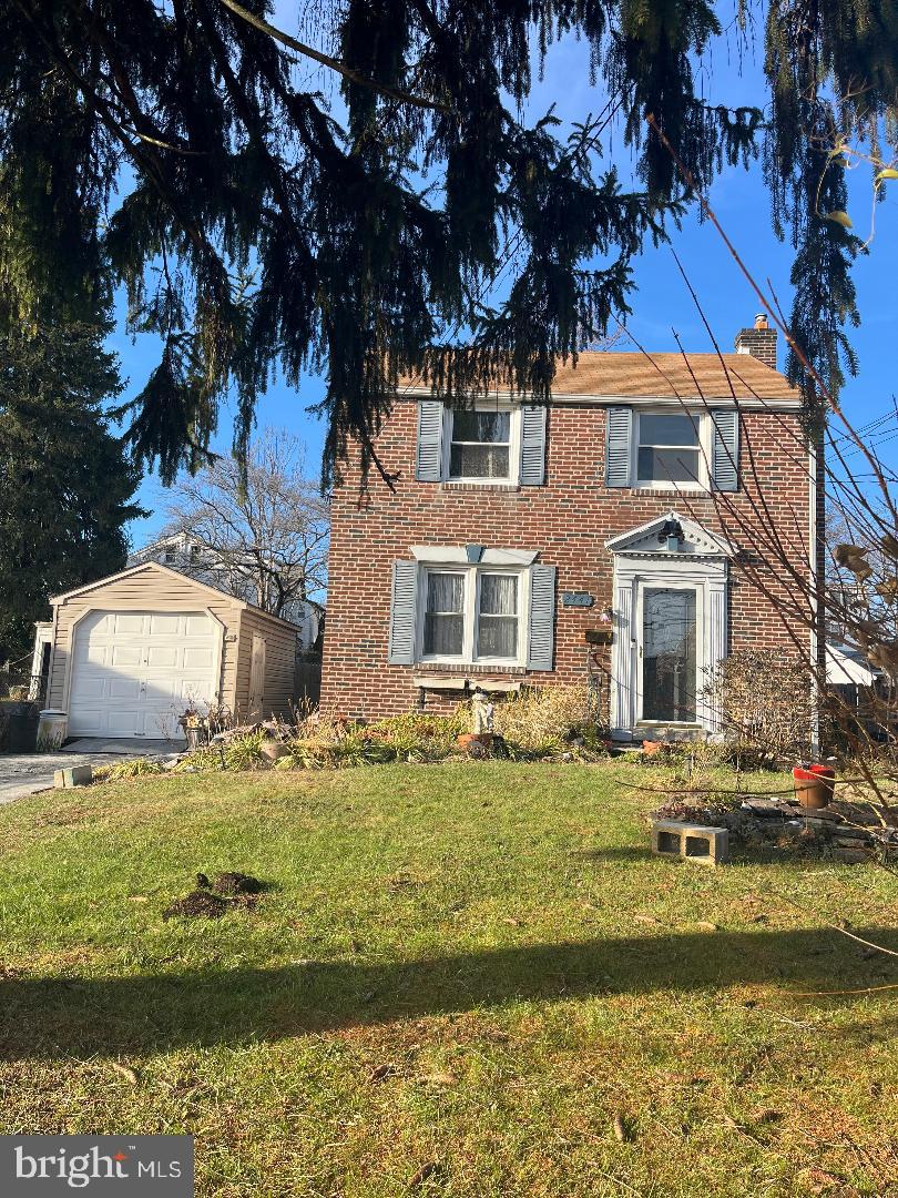 view of front facade with a garage, an outdoor structure, and a front lawn