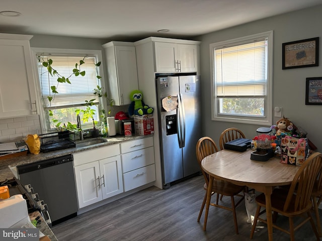 kitchen featuring white cabinetry, sink, tasteful backsplash, dark stone countertops, and appliances with stainless steel finishes