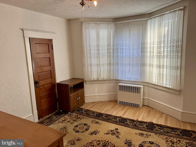 sitting room featuring radiator heating unit, plenty of natural light, and hardwood / wood-style floors