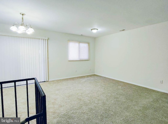 spare room featuring carpet and a notable chandelier