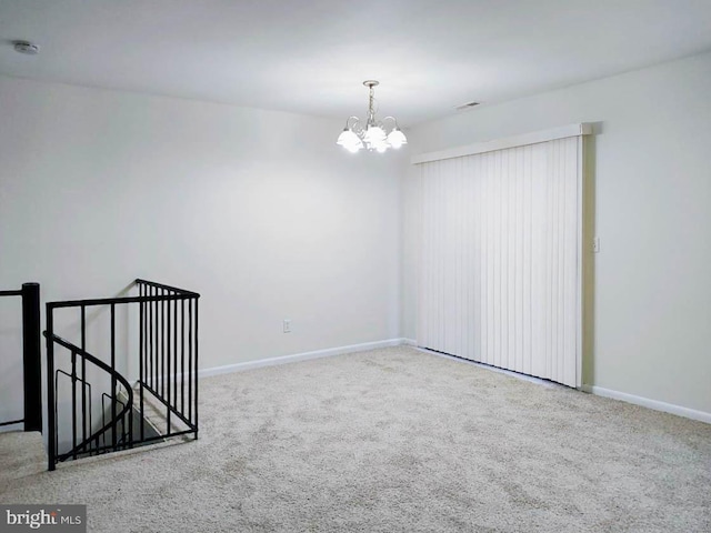 carpeted spare room with a notable chandelier