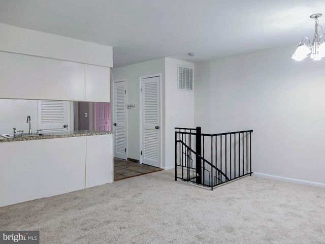 kitchen featuring sink, decorative light fixtures, an inviting chandelier, carpet floors, and white cabinetry