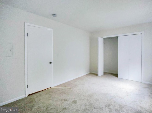 unfurnished bedroom featuring light carpet and a closet