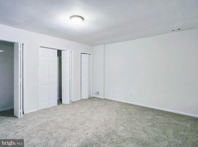 unfurnished bedroom featuring carpet and multiple closets