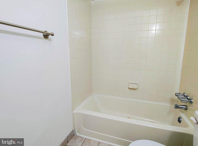 bathroom featuring tile patterned flooring, toilet, and tiled shower / bath