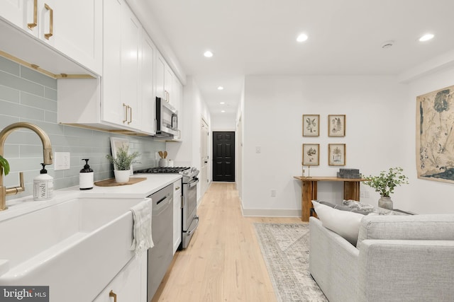 kitchen featuring stainless steel appliances, sink, white cabinets, and light hardwood / wood-style floors