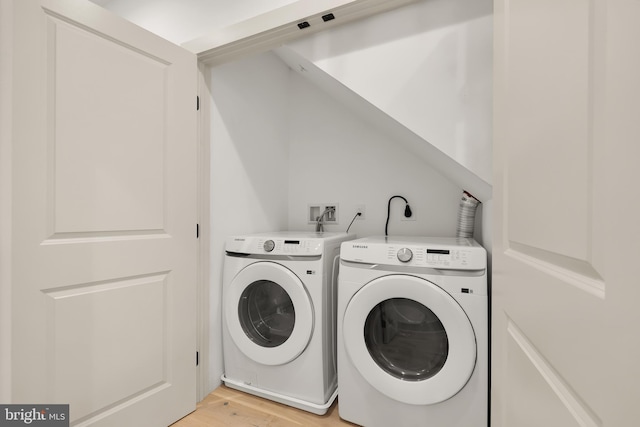 laundry area with washing machine and dryer and light wood-type flooring