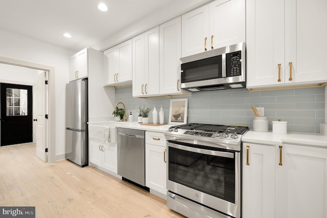 kitchen with white cabinetry, light wood-type flooring, backsplash, and appliances with stainless steel finishes