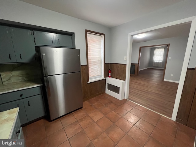 kitchen with stainless steel fridge, wooden walls, heating unit, and dark wood-type flooring