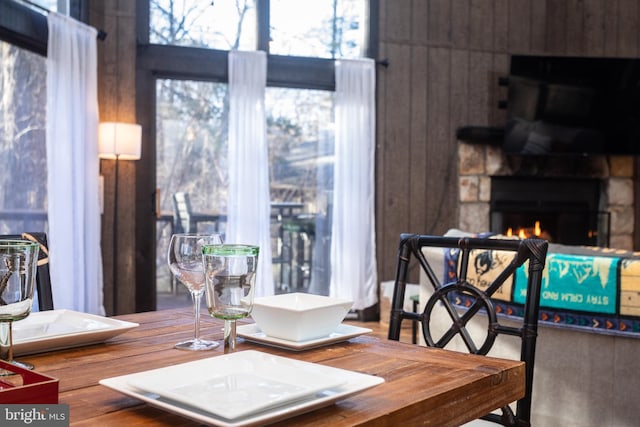 dining room featuring a stone fireplace, wooden walls, and hardwood / wood-style flooring