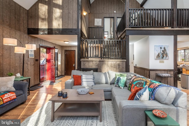 living room with wooden walls, high vaulted ceiling, and wood-type flooring