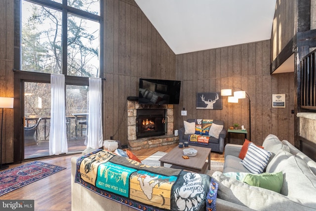 living room featuring wooden walls, a fireplace, high vaulted ceiling, and hardwood / wood-style flooring