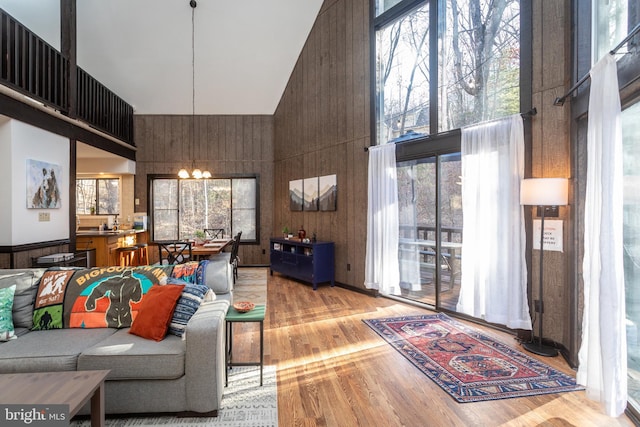 living room with a chandelier, light hardwood / wood-style flooring, high vaulted ceiling, and a wealth of natural light