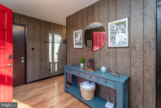 foyer entrance with wood walls and light hardwood / wood-style flooring