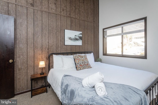 bedroom with light carpet and wood walls