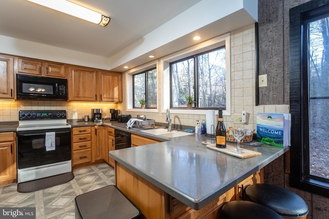 kitchen with kitchen peninsula, a wealth of natural light, a breakfast bar, and white electric range oven